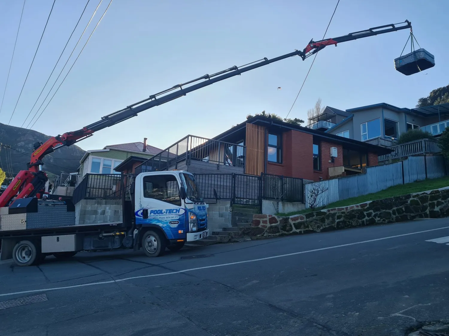 Crane truck relocating a spa up in the hills